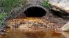 Orange acid mine drainage flows out of a pipe