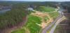 An aerial view shows evergreen woods, waterways, and meandering roads through fresh green grassy areas of a Bibb County, AL reclamation area.