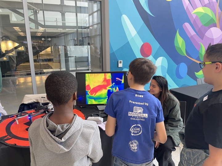 students engaging with Shauntelle Cruz, an OSM UAS pilot, and checking out the thermal camera attached to the UAS. 