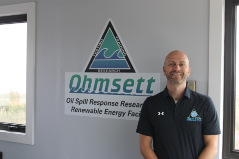 Brian Webster in front of Ohmsett logo.