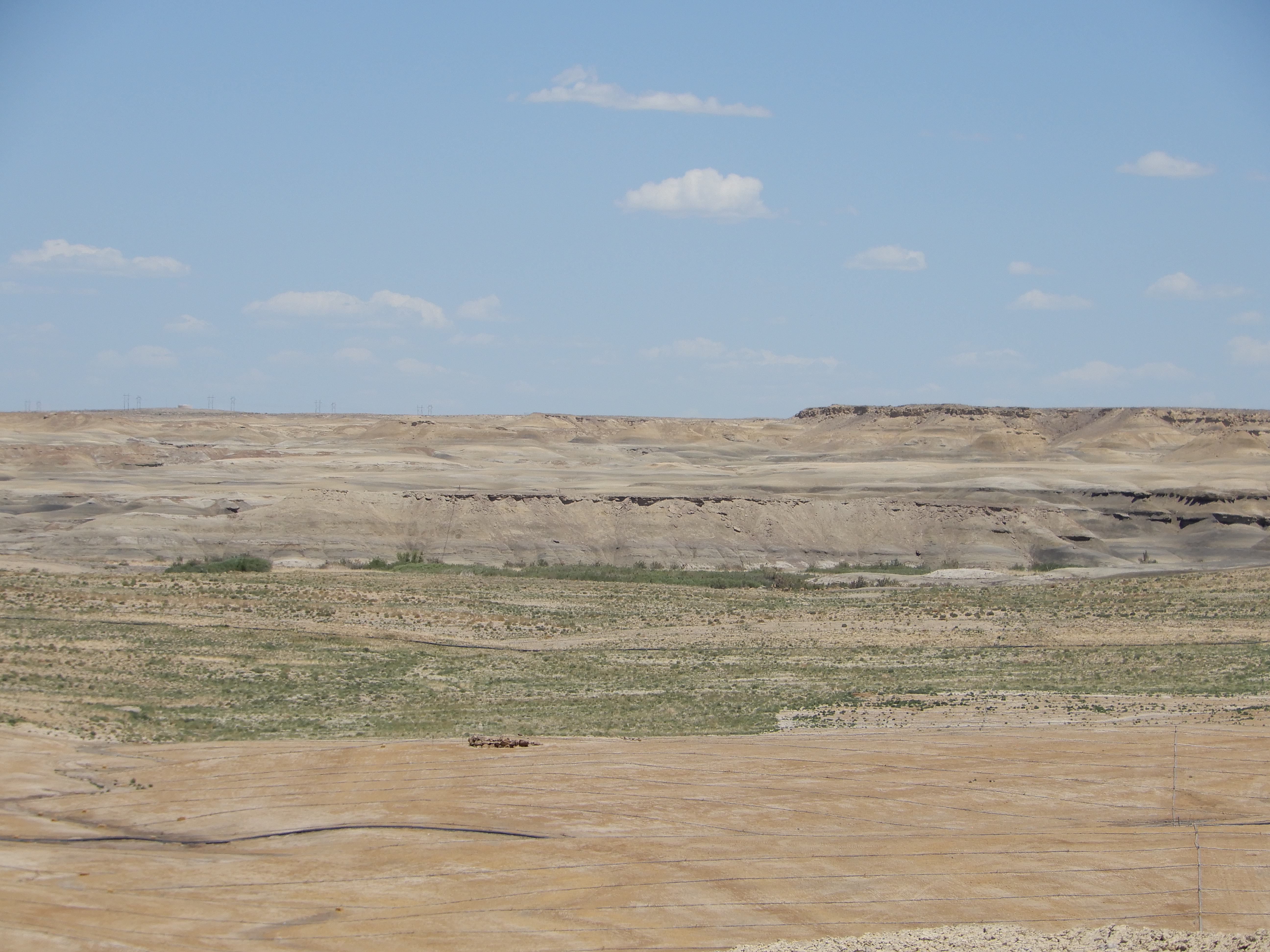 Photo of reclamation activities at the Navajo Mine. The photo has undisturbed badlands in the background and then different phase of reclamation in the foreground. The phase show fully reclaimed to newly topsoiled land. 