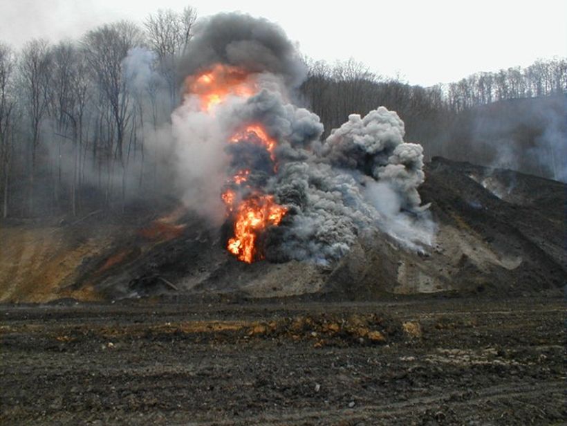 This image is an example of a burning refuse pile which has been mixed allowing more fuel (carbon) to reach the higher concentration of oxygen in the air.  A product of bring fresh fuel to the surface causes the flames flash or flare up.