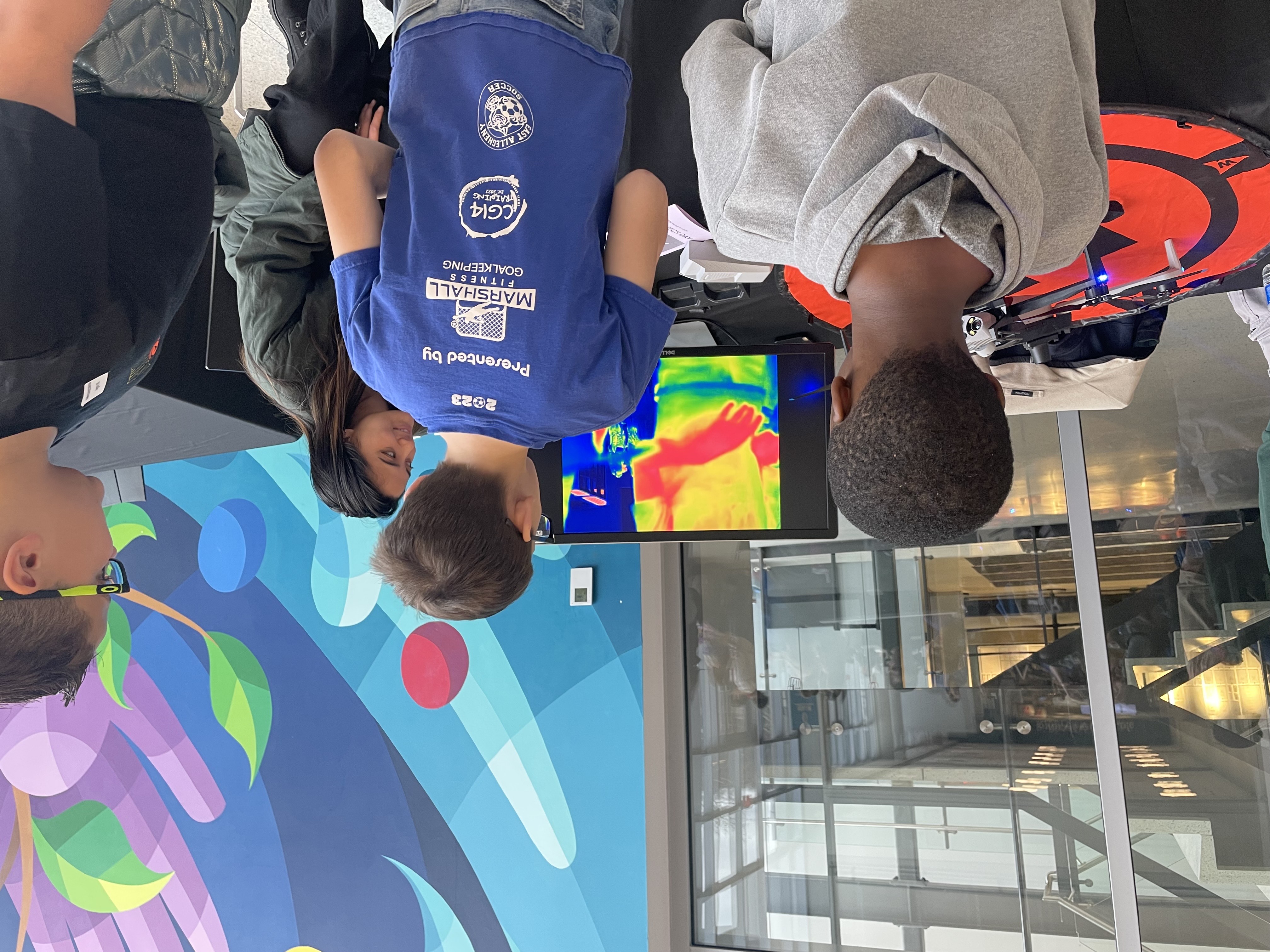 students engaging with Shauntelle Cruz, an OSM UAS pilot, and checking out the thermal camera attached to the UAS. 