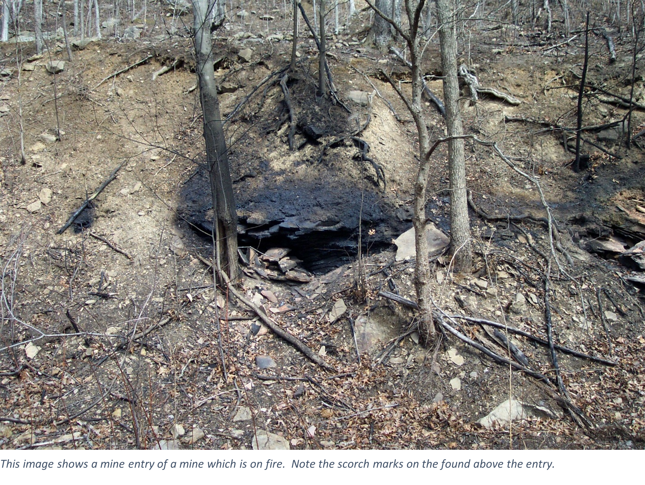 This image shows a mine entry of a mine which is on fire.  Note the scorch marks on the found above the entry.
