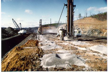 Blast site with drilling and earth moving equipment.