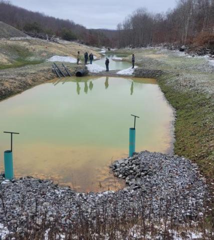 Acid mine drainage reclamation project shows 3 ponds and people in the background
