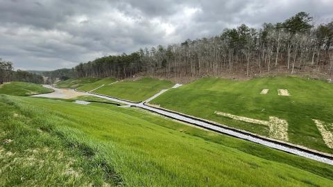 Image of post-construction mine land reclamation shows graded land, growing grass, and drainage infrastructure